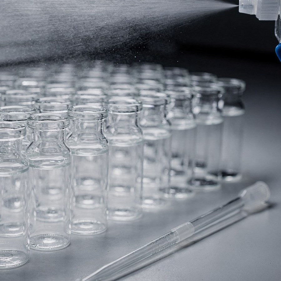 Rows of clear glass laboratory vials with a fine spray, representing studies of skin absorption