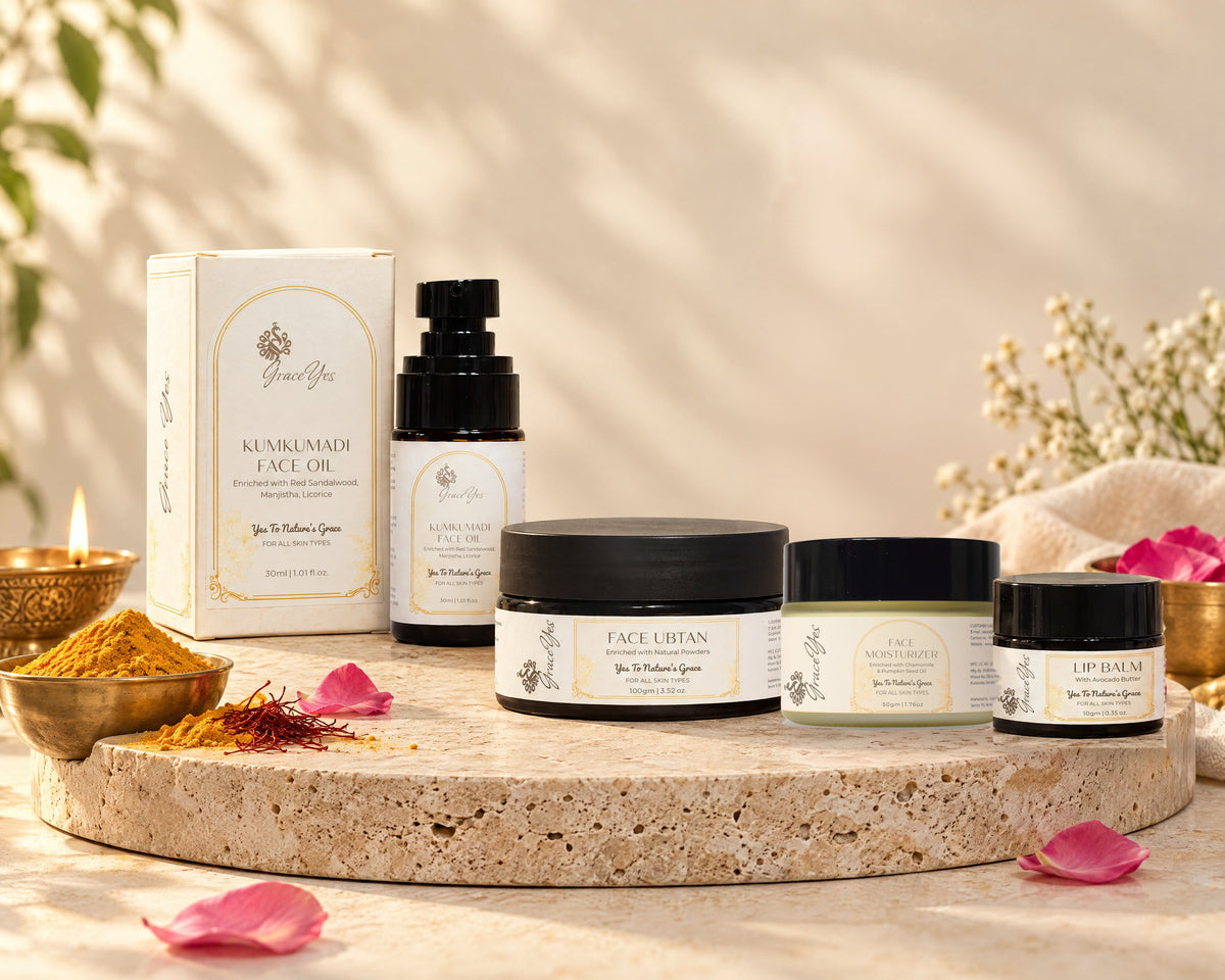 GraceYes Festive Glow Face Ritual Set: Kumkumadi Face Oil with its box, Face Ubtan, Face Moisturizer and Lip Balm on a stone plinth
