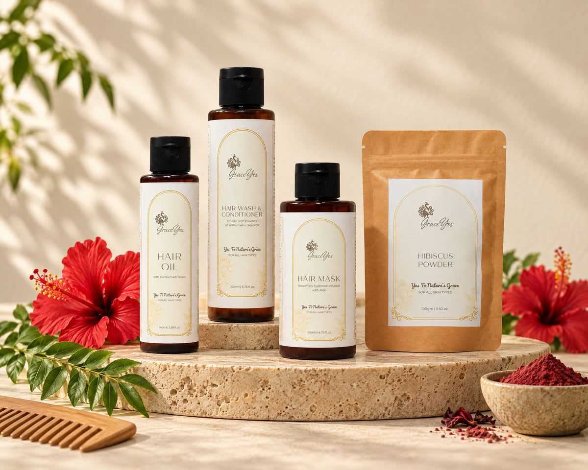 GraceYes Hair Ritual Gift Set: Hair Oil, Hair Wash & Conditioner, Hair Mask and Hibiscus Powder on a stone plinth with hibiscus flowers